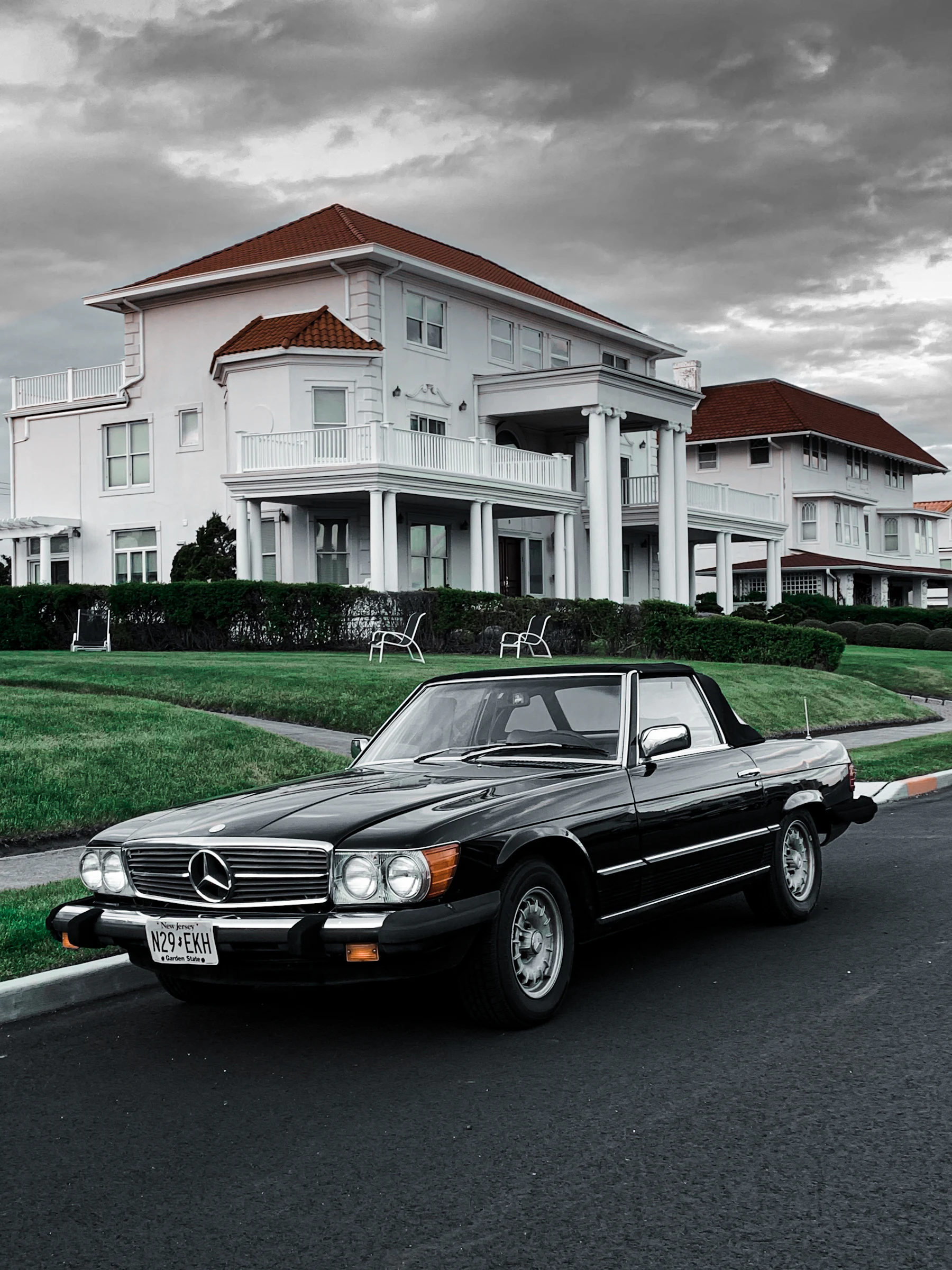 Classic black Mercedes-Benz SL outside a coastal residence.
