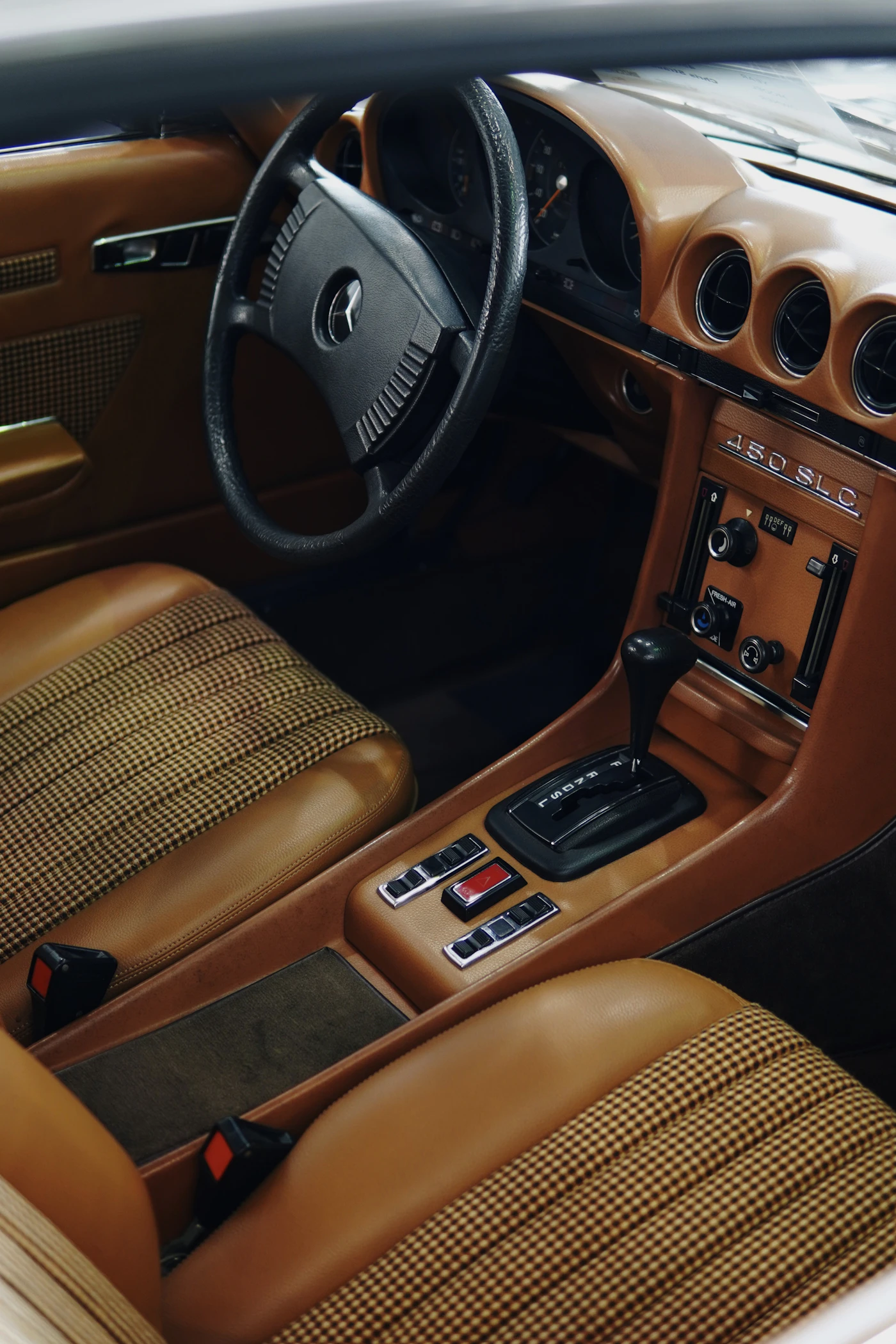 Cognac leather and patterned upholstery in a classic Mercedes-Benz 450 SLC cabin.